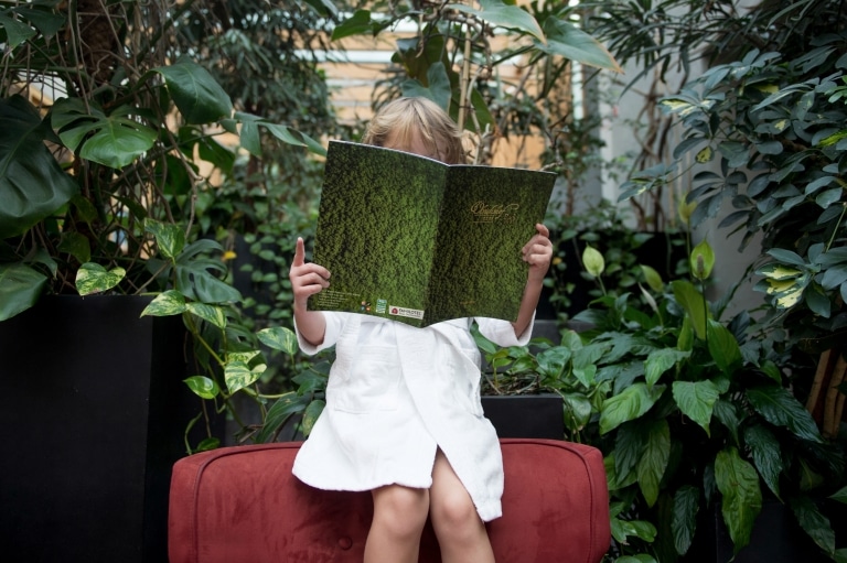 Mädchen liest ULRICHSHOF Wald-SPA Broschüre