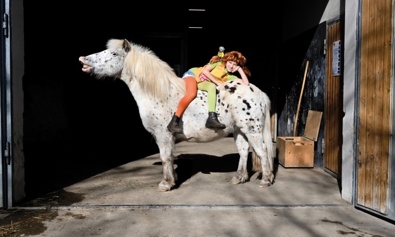Mädchen als Pippi Langstrumpf sitzt auf einem Pony im ULRICHSHOF, mit buntem Kostüm und fröhlicher Abenteuerszene im Stallbereich